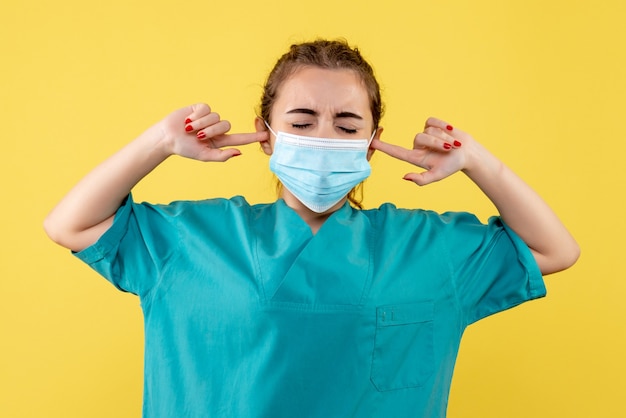Free photo front view female doctor in medical shirt and mask stucked her ears, color pandemic health virus covid-19 uniform