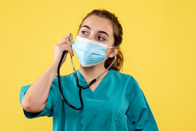 Front view female doctor in medical shirt and mask with stethoscope, virus uniform color emotion covid health