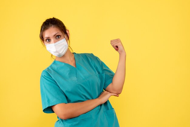 Foto gratuita medico femminile vista frontale in camicia medica e maschera su sfondo giallo