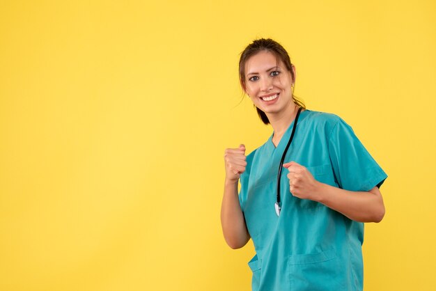 노란색 배경에 웃 고 의료 셔츠에 전면보기 여성 의사