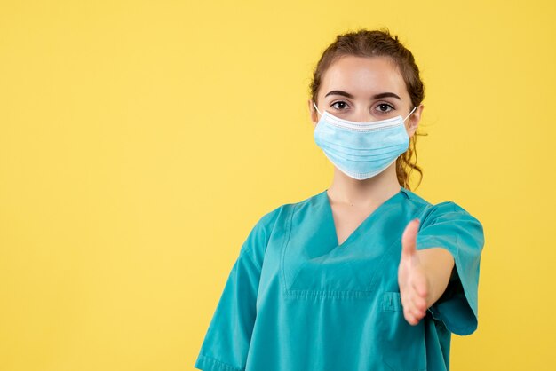 Front view female doctor in medical shirt and sterile mask, color health uniform covid-19 virus