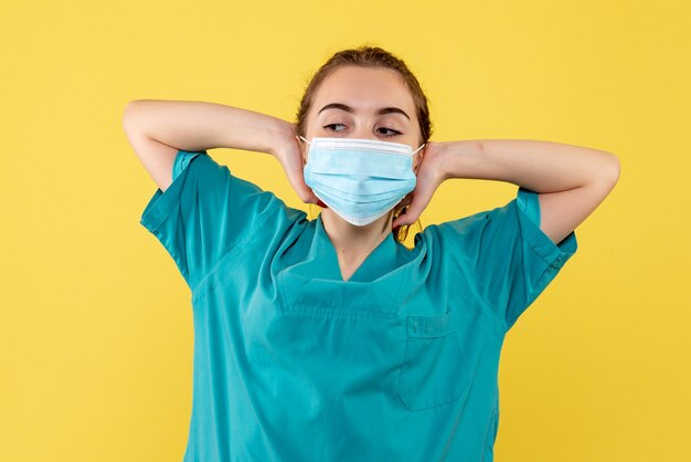 Front view female doctor in medical shirt and sterile mask, health pandemic color covid-19 virus uniform