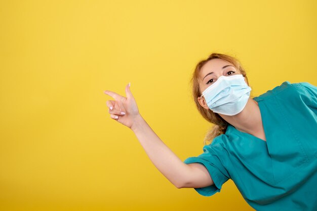 Front view female doctor in medical shirt and sterile mask, hospital color covid-19 health emotion pandemic