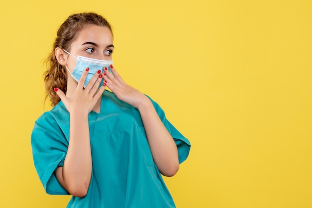 Medico femminile di vista frontale in camicia medica e maschera sterile, salute pandemica di coronavirus del virus covid-19 uniforme