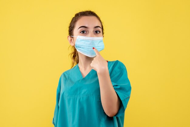 Medico femminile di vista frontale in camicia medica e maschera sterile, salute covid di emozione di colore uniforme del virus