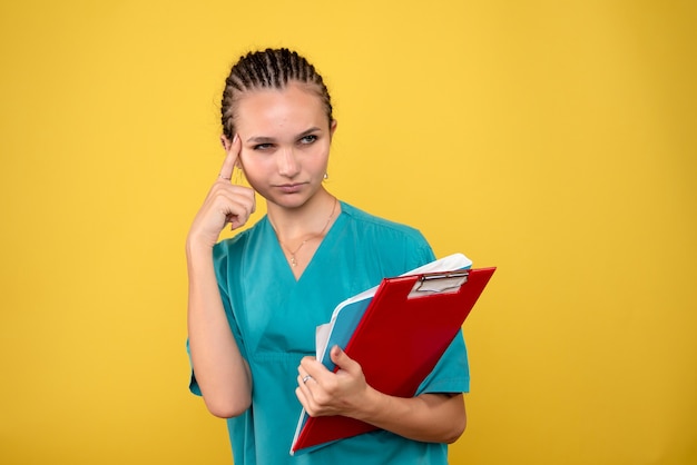 Foto gratuita medico femminile di vista frontale in camicia medica con differenti note, infermiera covid-19 infermiera sanitaria di colore di emozione dell'ospedale