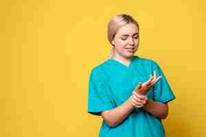 Foto gratuita medico femminile di vista frontale in camicia medica con braccio ferito, emozione covid-19 del medico dell'infermiere pandemico
