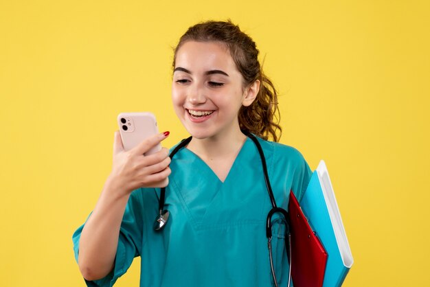 Front view female doctor in medical shirt with notes and phone, emotion uniform pandemic health covid-19 virus