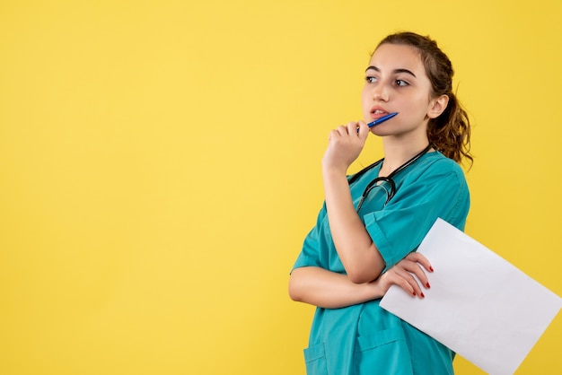 Front view female doctor in medical shirt with papers and stethoscope, uniform pandemic health covid-19 emotion virus