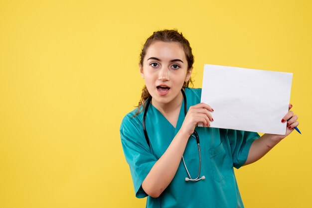 Вид спереди женщина-врач в медицинской рубашке с бумагами и стетоскопом, пандемия вируса covid-19, равномерная эмоция