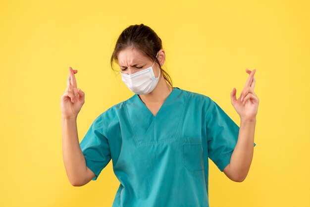 Front view female doctor in medical shirt with sterile mask on yellow background