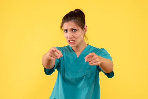 Front view female doctor in medical shirt on a yellow background