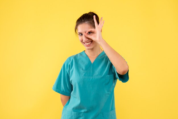 Front view female doctor in medical shirt on a yellow background