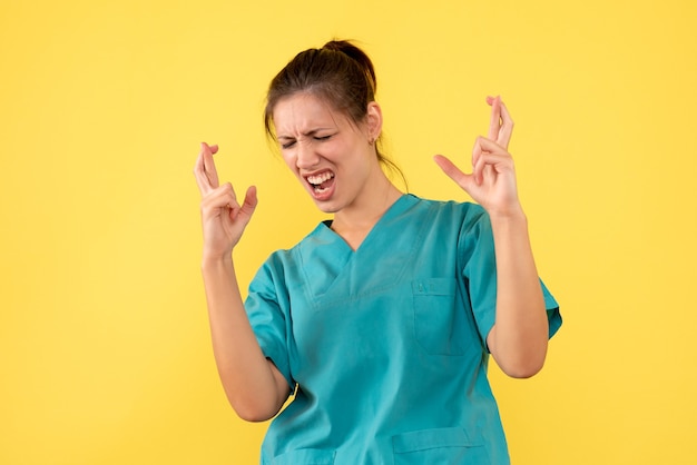 Front view female doctor in medical shirt on a yellow background