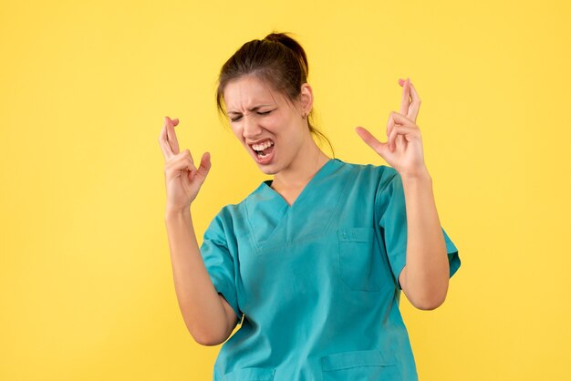 Front view female doctor in medical shirt on a yellow background