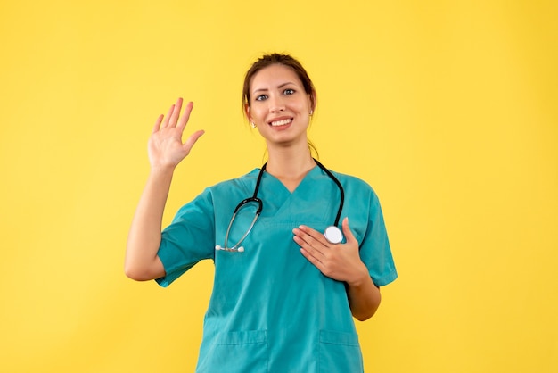 Front view female doctor in medical shirt on a yellow background