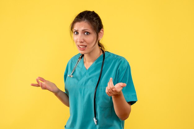 Front view female doctor in medical shirt on a yellow background