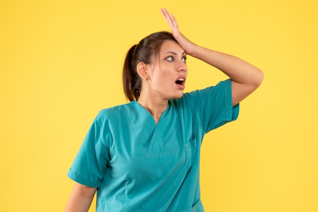 Front view female doctor in medical shirt on a yellow background