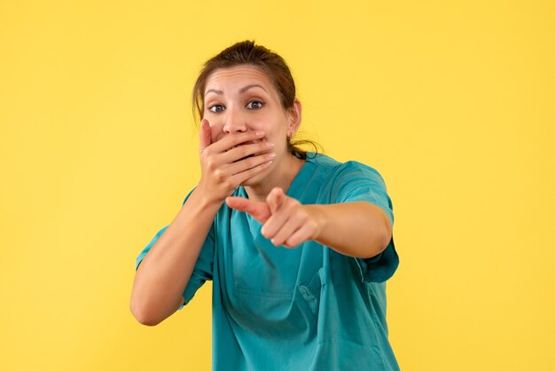 Front view female doctor in medical shirt on a yellow background