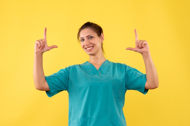 Front view female doctor in medical shirt on a yellow background