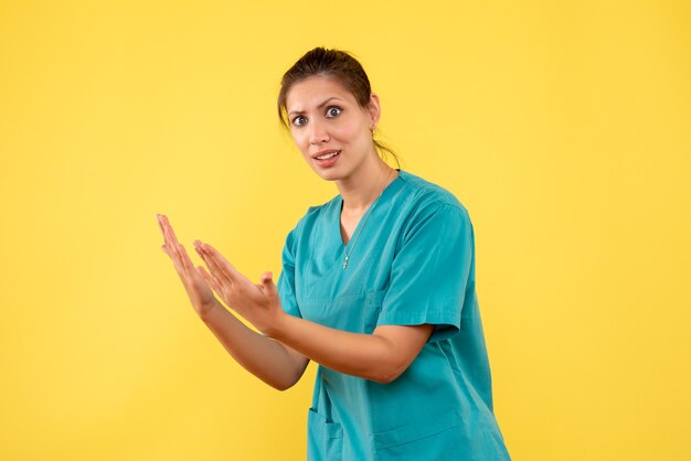 노란색 배경에 의료 셔츠에 전면보기 여성 의사