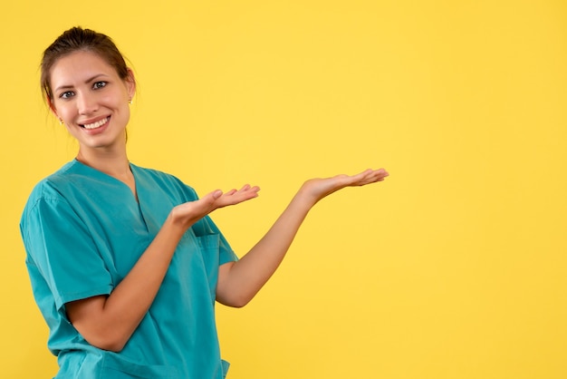 Foto gratuita medico femminile di vista frontale in camicia medica su una priorità bassa gialla