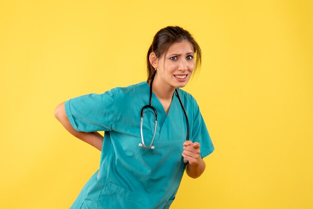 Front view female doctor in medical shirt on the yellow background