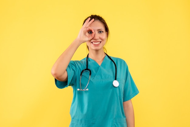 Foto gratuita medico femminile di vista frontale in camicia medica su una priorità bassa gialla