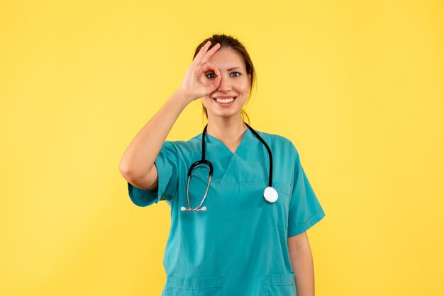 Front view female doctor in medical shirt on the yellow background