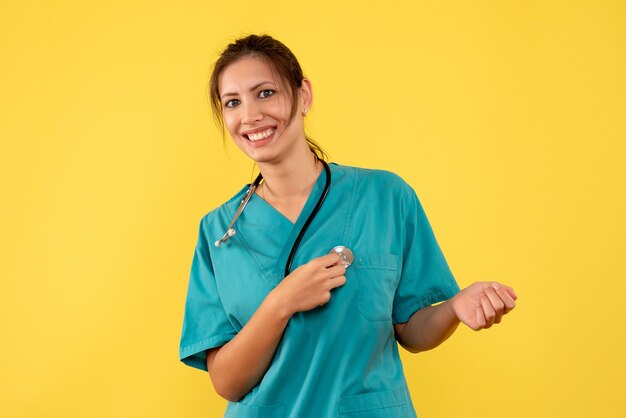 Front view female doctor in medical shirt on the yellow background