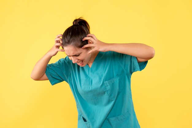 Foto gratuita medico femminile di vista frontale in camicia medica su una priorità bassa gialla