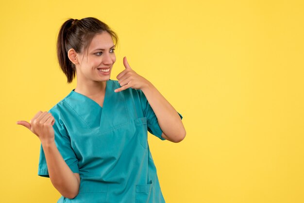 Front view female doctor in medical shirt on the yellow background