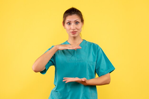 Front view female doctor in medical shirt on the yellow background