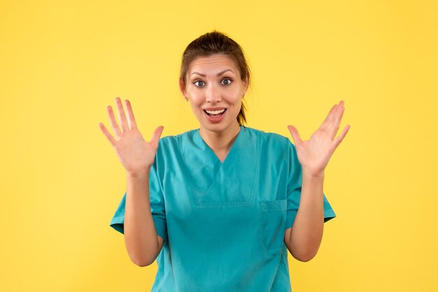 Front view female doctor in medical shirt on the yellow background
