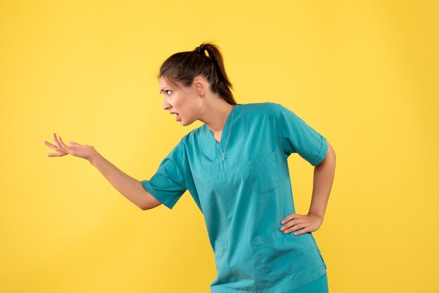 Front view female doctor in medical shirt on the yellow background