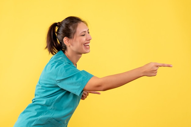 Front view female doctor in medical shirt on the yellow background