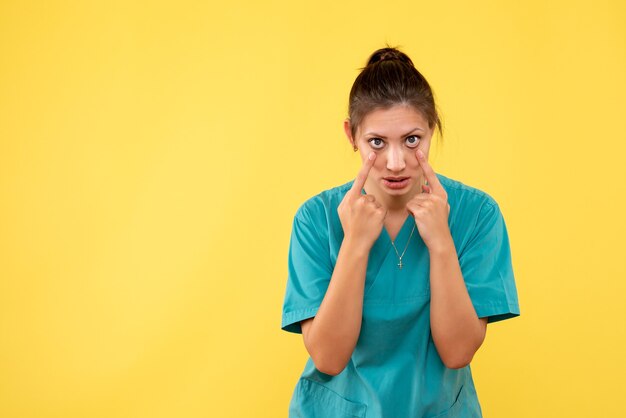 Front view female doctor in medical shirt on the yellow background