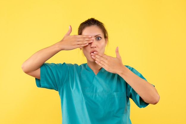 Front view female doctor in medical shirt on the yellow background