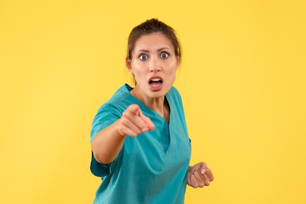 Front view female doctor in medical shirt on yellow background