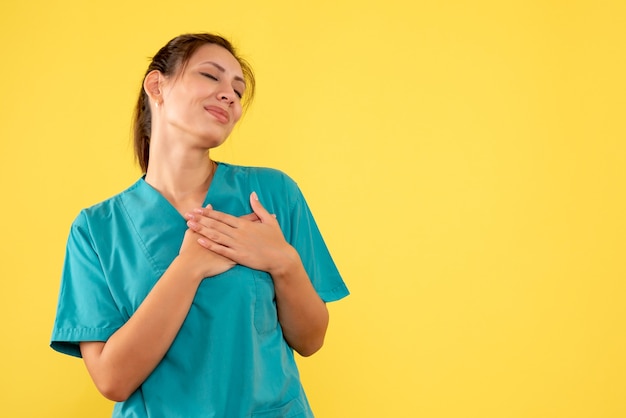 Front view female doctor in medical shirt on yellow background