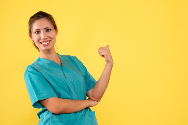 Front view female doctor in medical shirt on yellow background