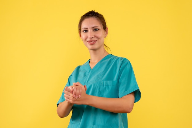 Front view female doctor in medical shirt on yellow background