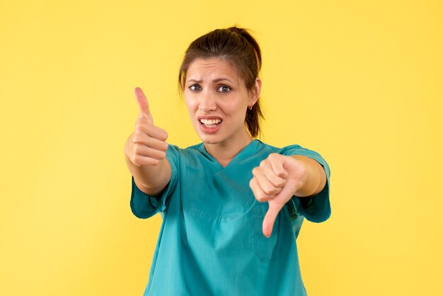 Front view female doctor in medical shirt on yellow background