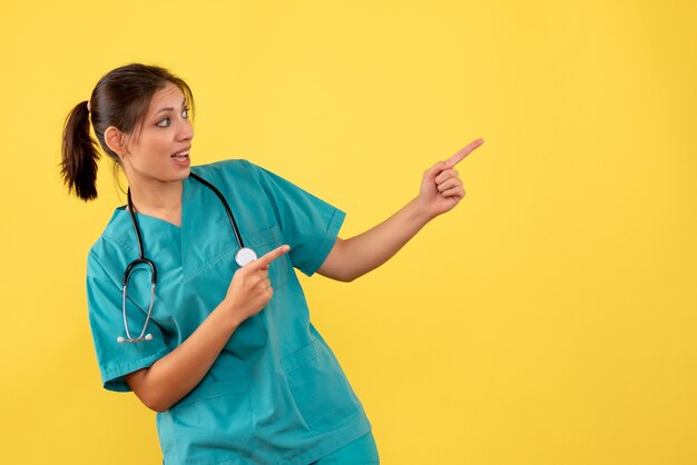 Front view female doctor in medical shirt on yellow background