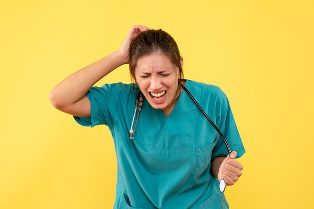 Front view female doctor in medical shirt on yellow background