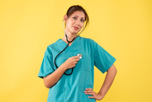 Front view female doctor in medical shirt on yellow background