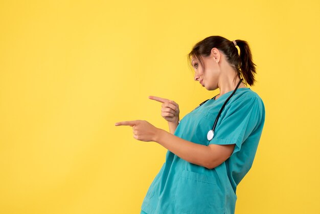 Front view female doctor in medical shirt on yellow background