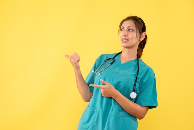 Front view female doctor in medical shirt on yellow background