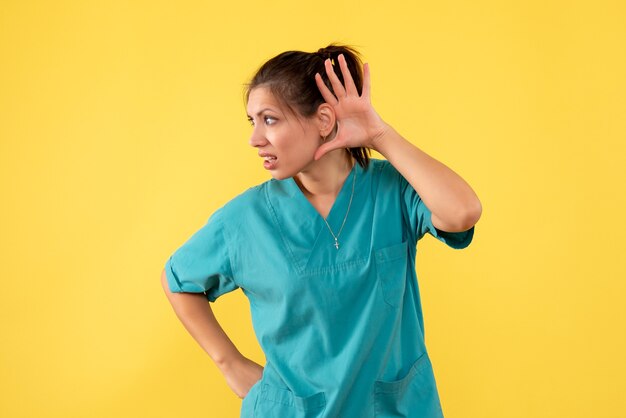 Front view female doctor in medical shirt on yellow background