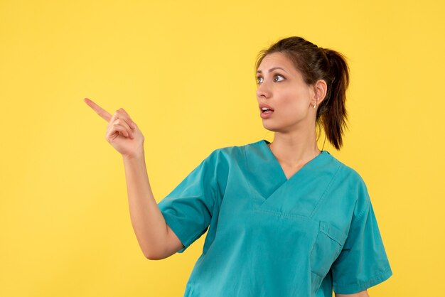 Front view female doctor in medical shirt on yellow background